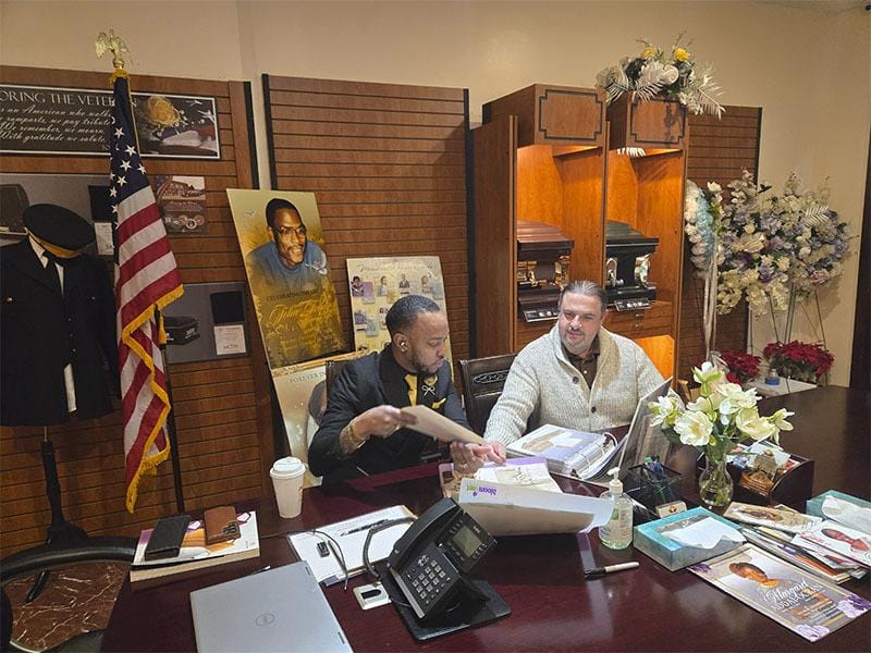 Funeral directors assisting a family member in a private arrangement room at Harmony Funeral Home in Brooklyn.