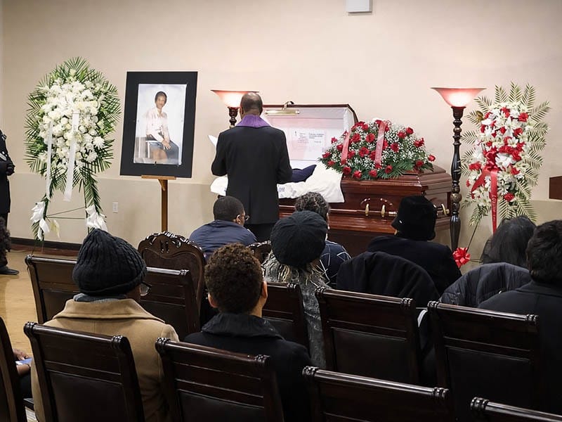 Christian funeral service ceremony arranged by Harmony Funeral Home at 2200 Clarendon Rd in Brooklyn NY with cross, candles and floral tribute