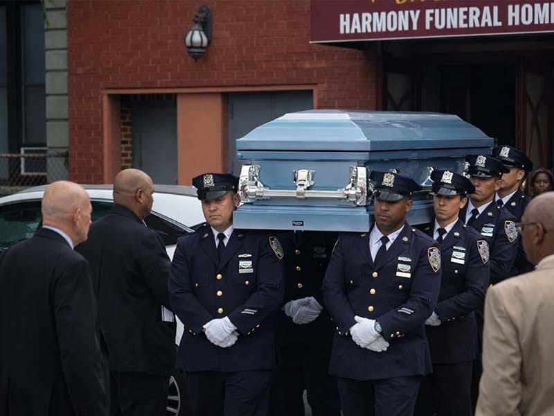 Military honor guard carrying casket during veteran funeral service arranged by Harmony Funeral Home in Brooklyn NY