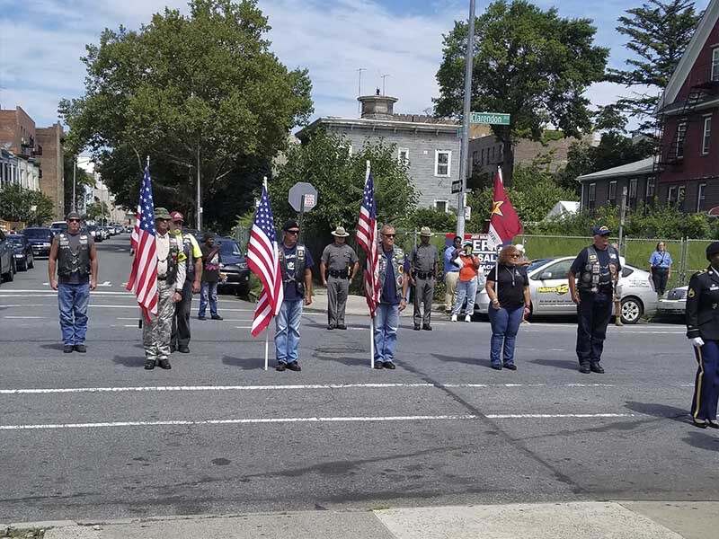 Veteran funeral procession with American flags honoring a service member in Brooklyn NY by Harmony Funeral Home